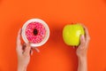 Hands showing an apple and a donut as a healthy lifestyle concept. Young woman choosing between green apple or junk food Royalty Free Stock Photo