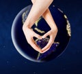 Hands showing heart gesture over earth in space Royalty Free Stock Photo