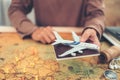 Hands showing model airplane and passport above world map and book, magnifying glass, compass and camera on map. Travel , Royalty Free Stock Photo