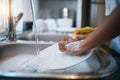 Hands, sink and cleaning dishes with a person in the kitchen of a home to wash a plate for hygiene. Water, bacteria and Royalty Free Stock Photo