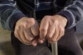 Hands of an elderly man leaning on his walking stick