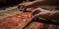 Hands skillfully weave a vibrant, handmade rug, displaying the artisan dedication to preserving an ancient tradition