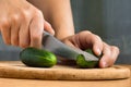 Hands slicing cucumber on wooden cutting board Royalty Free Stock Photo