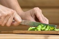 Hands slicing cucumber on the wooden cutting board Royalty Free Stock Photo