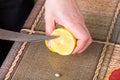 Hands slicing lemon with knife. Royalty Free Stock Photo