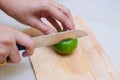 Hands slicing a lime with a chef knife