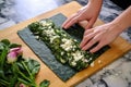 hands slicing a spinach and feta flatbread pizza on a marble countertop