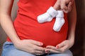 Hands in small socks on the stomach of a pregnant woman