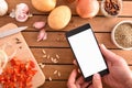 Hands with smartphone in kitchen preparing a menu top Royalty Free Stock Photo