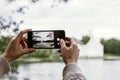 Hands with a smartphone in the Park, girl takes photo in nature