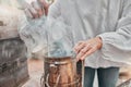 Hands, smoker fire and beekeeper on farm mix and refueling with tool. Safety, beekeeping and worker in suit preparing