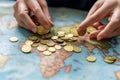 Hands sorting coins on a world map showing various continents and countries in a study or office setting Royalty Free Stock Photo