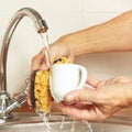 Hands with sponge wash the coffee cup under running water in kitchen