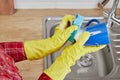 Hands with sponge wash the cup under water, housewife in protective gloves manually washing blue mug. Hand cleaning Royalty Free Stock Photo