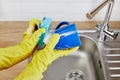 Hands with sponge wash the cup under water, housewife woman in yellow rubber protective gloves washing blue mug Royalty Free Stock Photo