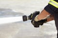 Hands, spray and nozzle for water, firefighter and help in emergency, brave or stop inferno in uniform. Fireman, fire Royalty Free Stock Photo