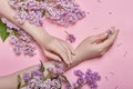 Hands and spring flowers are on a pink table skincare. Nature Cosmetics for hand skin care, a means to reduce wrinkles on hands,