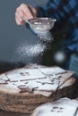 Hands sprinkle gingerbread cookies with powdered sugar through a strainer. grainy film effect.