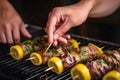 hands squeezing lemon over grilled lamb kebabs