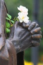 Hands of a statue in pious attitude and white flowers Royalty Free Stock Photo