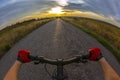 Hands on the steering wheel riding a cyclist on the road towards sunset