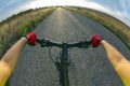 Hands on the steering wheel riding a cyclist on the road towards sunset