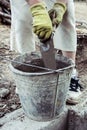 Hands of a woman with gloves stirring cement