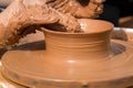 Hands of a street potter make a clay pot on a potter`s wheel.