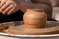 Hands of a street potter make a clay pot on a potter`s wheel. Royalty Free Stock Photo