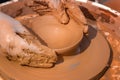 Hands of a street potter make a clay pot on a potter`s wheel. Royalty Free Stock Photo