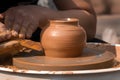 Hands of a street potter make a clay pot on a potter`s wheel. Royalty Free Stock Photo