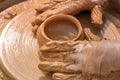 Hands of a street potter make a clay pot on a potter`s wheel. Royalty Free Stock Photo