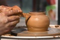 Hands of a street potter make a clay pot on a potter`s wheel.