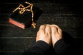 Hands on a table made of boards with a book with a rosary