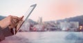 Hands with tablet against blurry skyline and red overlay Royalty Free Stock Photo
