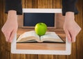 Hands with tablet on table showing book with green apple Royalty Free Stock Photo