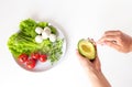 Hands take avocado with a spoon. Raw healthy vegetarian food. Vegetables, mozzarella and olive oil on white background, top view Royalty Free Stock Photo