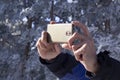 Hands take a mobile phone to take a picture of snowy nature