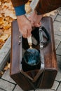 Hands take out magnifying glass from leather carpetbag on autumn alley