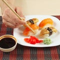 Hands taking ginger with chopsticks. Sushi with omelet with eel and with salmon and soy sauce with ginger and wasabi Royalty Free Stock Photo