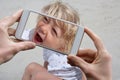 Hands taking a photo with a mobile phone of a laughing little child in summer holidays Royalty Free Stock Photo