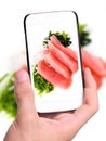 Hands taking photo pieces of tuna and salad with smartphone
