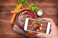 Hands taking photo red beetroot soup with smartphone. Royalty Free Stock Photo