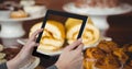 Hands taking picture of sweet food with tablet PC in coffee shop