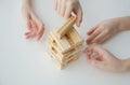 hands taking or putting a block to an unstable and incomplete tower of wooden blocks. Concept photo of planning, taking Royalty Free Stock Photo