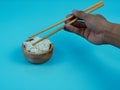 hands taking rice in small wooden bowl with chopsticks Royalty Free Stock Photo