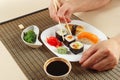 Hands taking sushi with chopsticks. Sushi with omelet with unagi and with salmon, rolls, hiyashi wakame salad and soy sauce