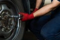 Hands of technician using a torque wrench to remove car wheel bolts - Low view of a auto repair mechanic operating hand