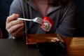 The hands of a teenager in a gray hoodie are holding sushi food with a European device with an iron fork Royalty Free Stock Photo