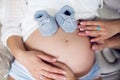 Hands of their parents, dressed in white, holding a knitted blue booties Royalty Free Stock Photo